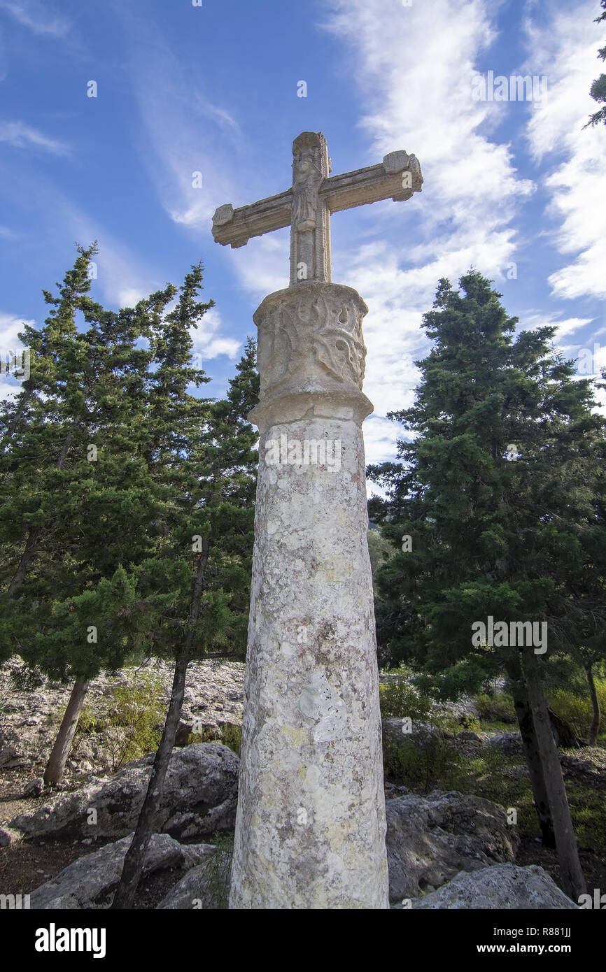 Weißer Stein Kreuz stehend auf Skulpturen aus Kalkstein im immergrünen Wald in der Nähe des Kloster Lluc, Mallorca, Balearen, Spanien. Stockfoto