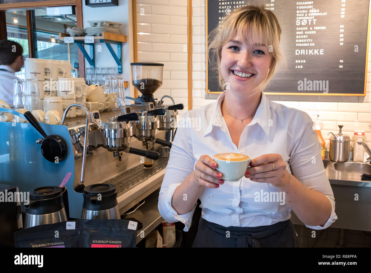 Tromsø, Norwegen - 18 August, 2018: eine junge Frau barista zeigen eine nur Cappuccino in einem Café in Tromsø, Norwegen. Stockfoto