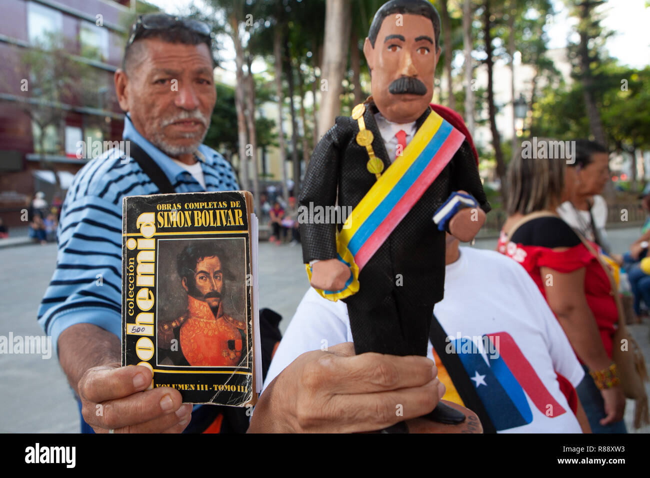 Mann mit Buch und Frau mit politischen Statuette in Bolivar Square, Porträt, Caracas, Venezuela, Südamerika Stockfoto