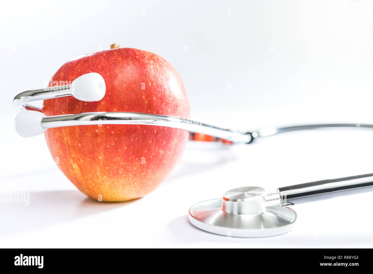 Stethoskop mit einem Apple am weißen Tisch Stockfoto