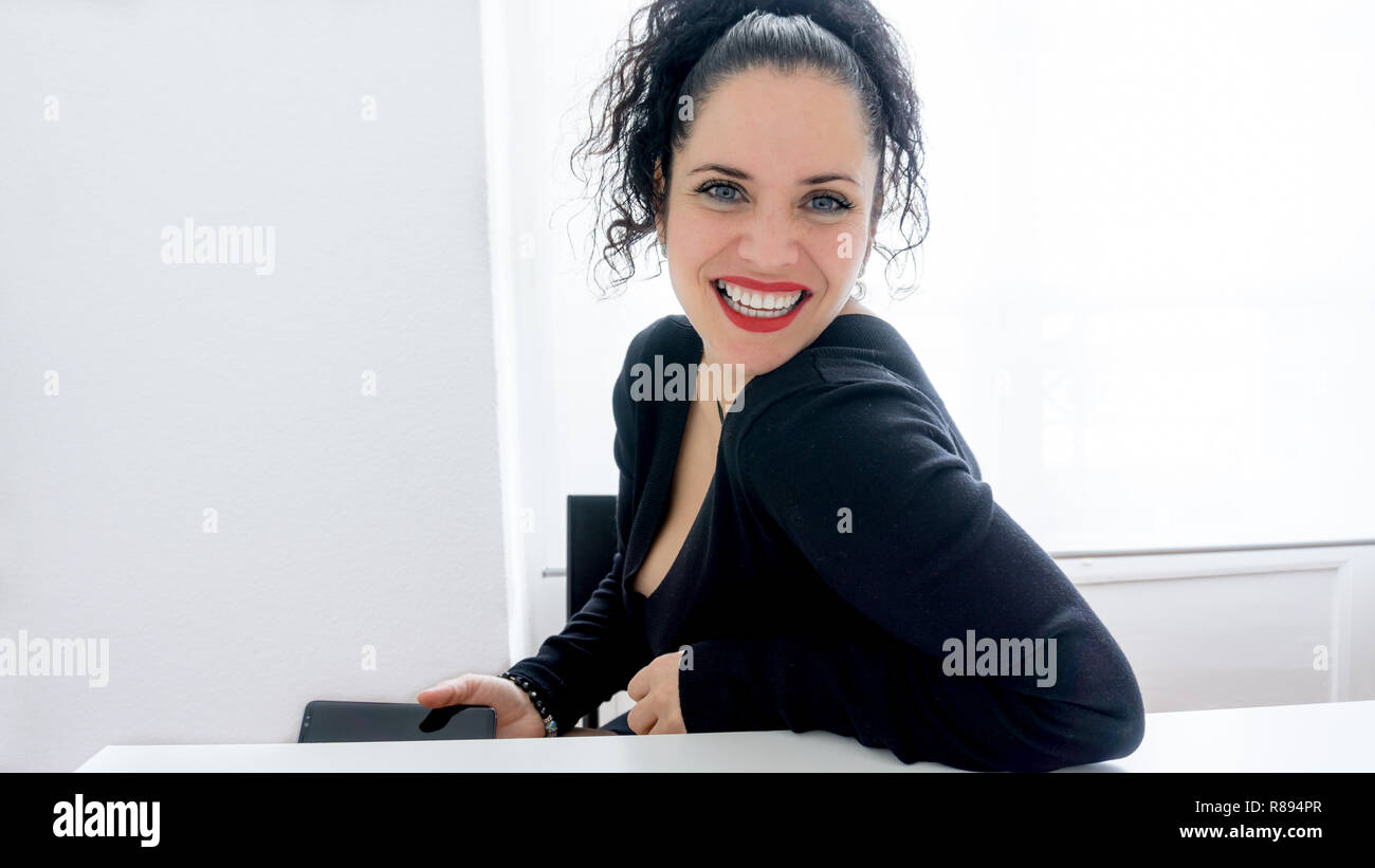 Porträt einer wunderschönen normale Frau mit ihrem Mobiltelefon und lächelnd mit schwarzem Haar, weiße Haut und rote Lippen. Platz kopieren Stockfoto