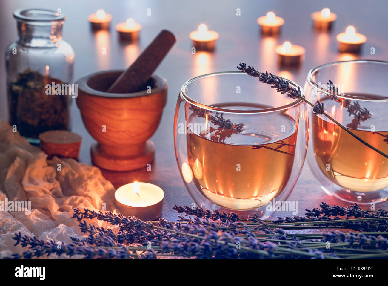 Pflanzliche teain ein Glas Tassen mit Lavendel auf einem Tisch mit Kerzenlicht Stockfoto