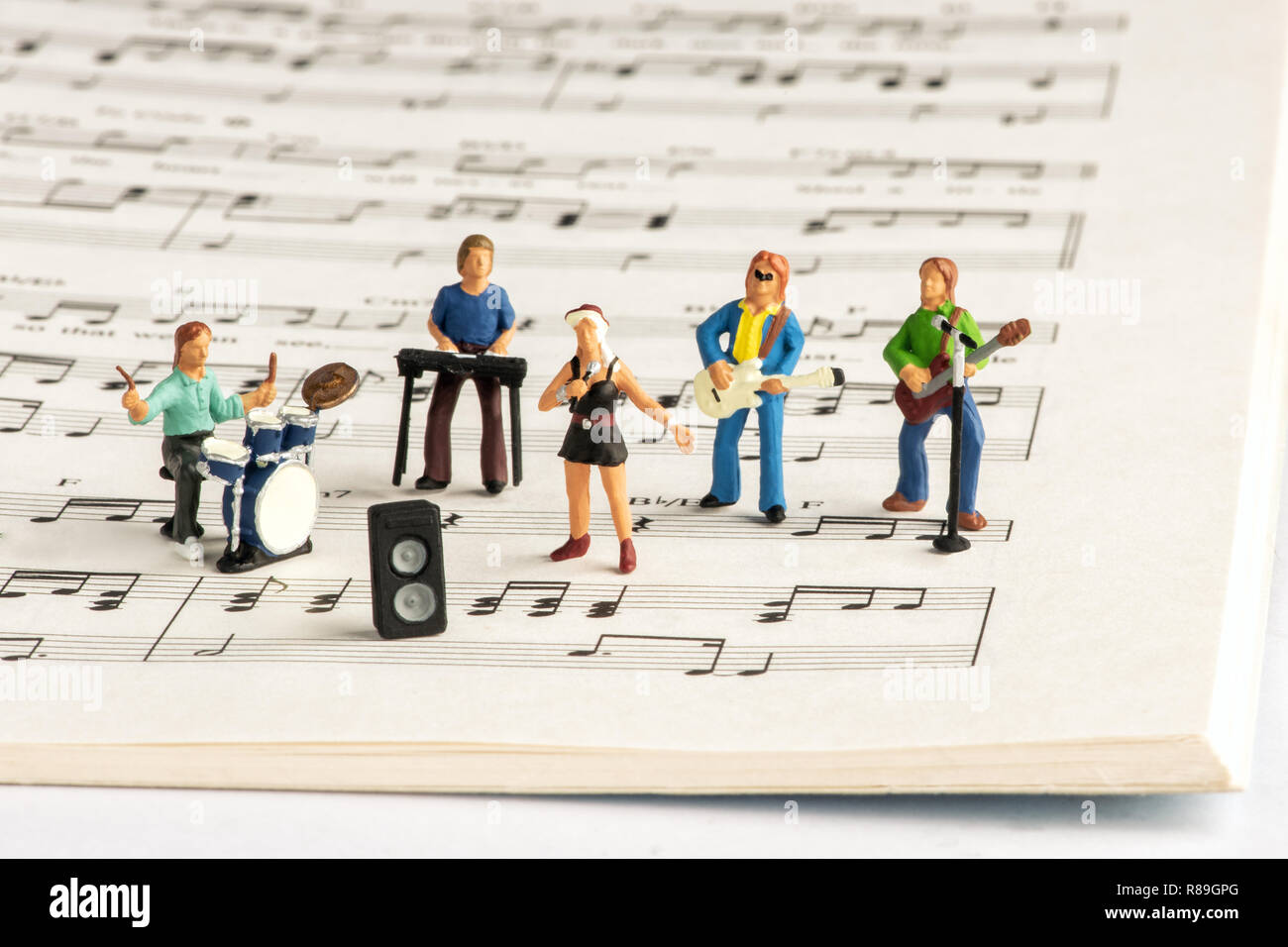 Rock Band miniatur Menschen spielen Konzert auf offenen musikalischen Notebook mit Noten Stockfoto