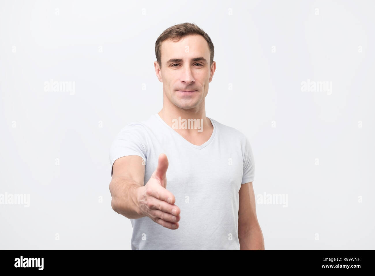 Junge Mann gibt Handshake, grüßt mit jemand,, freut sich treffen. Stockfoto