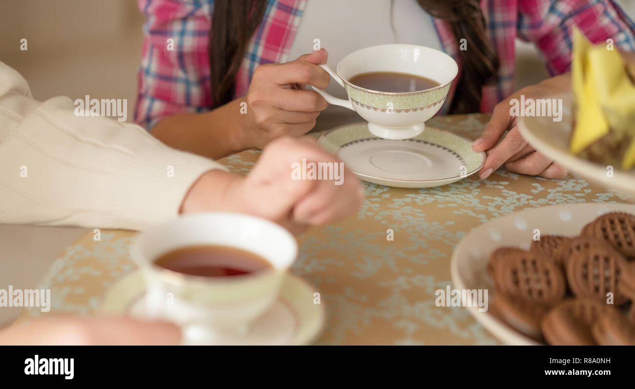 Nahaufnahme von der Frau Hände halten eine Tasse Tee aus Keramik. Zarte weiße Porzellan Tassen und Teller Stockfoto