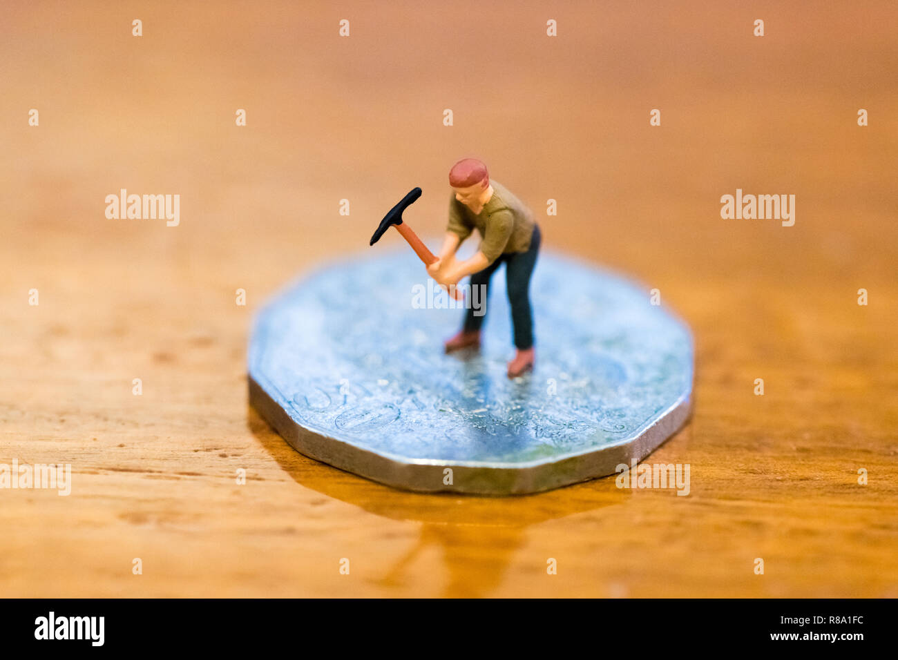 Miniatur Figur als Miner graben Münze, die manuelle Arbeit für Geld, über Holz- Hintergrund isoliert Stockfoto