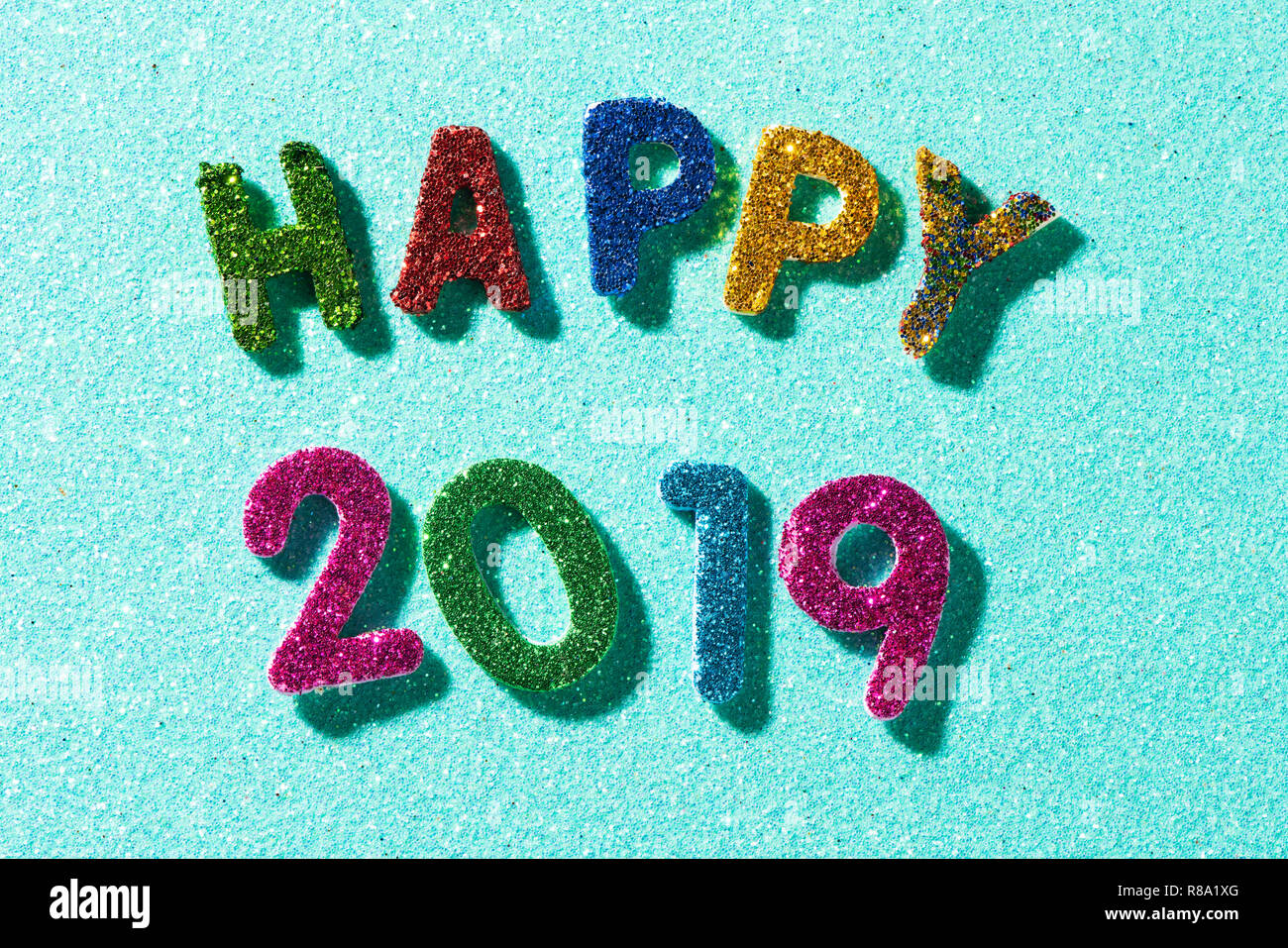 Nahaufnahme von einigen glitter Buchstaben und Zahlen in verschiedenen Farben, die den Text gerne 2019, auf einem blauen Glitzer Hintergrund Stockfoto