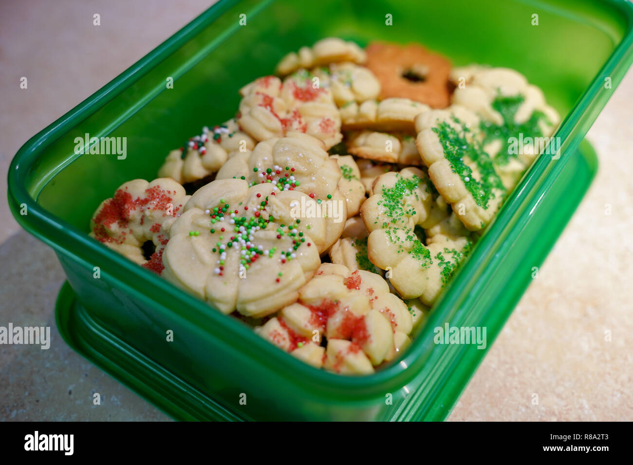 Hausgemachte Butter spritz Weihnachtsplätzchen verpackt in einem grünen Kunststoffbehälter für einfachen Transport zu einer Partei Stockfoto