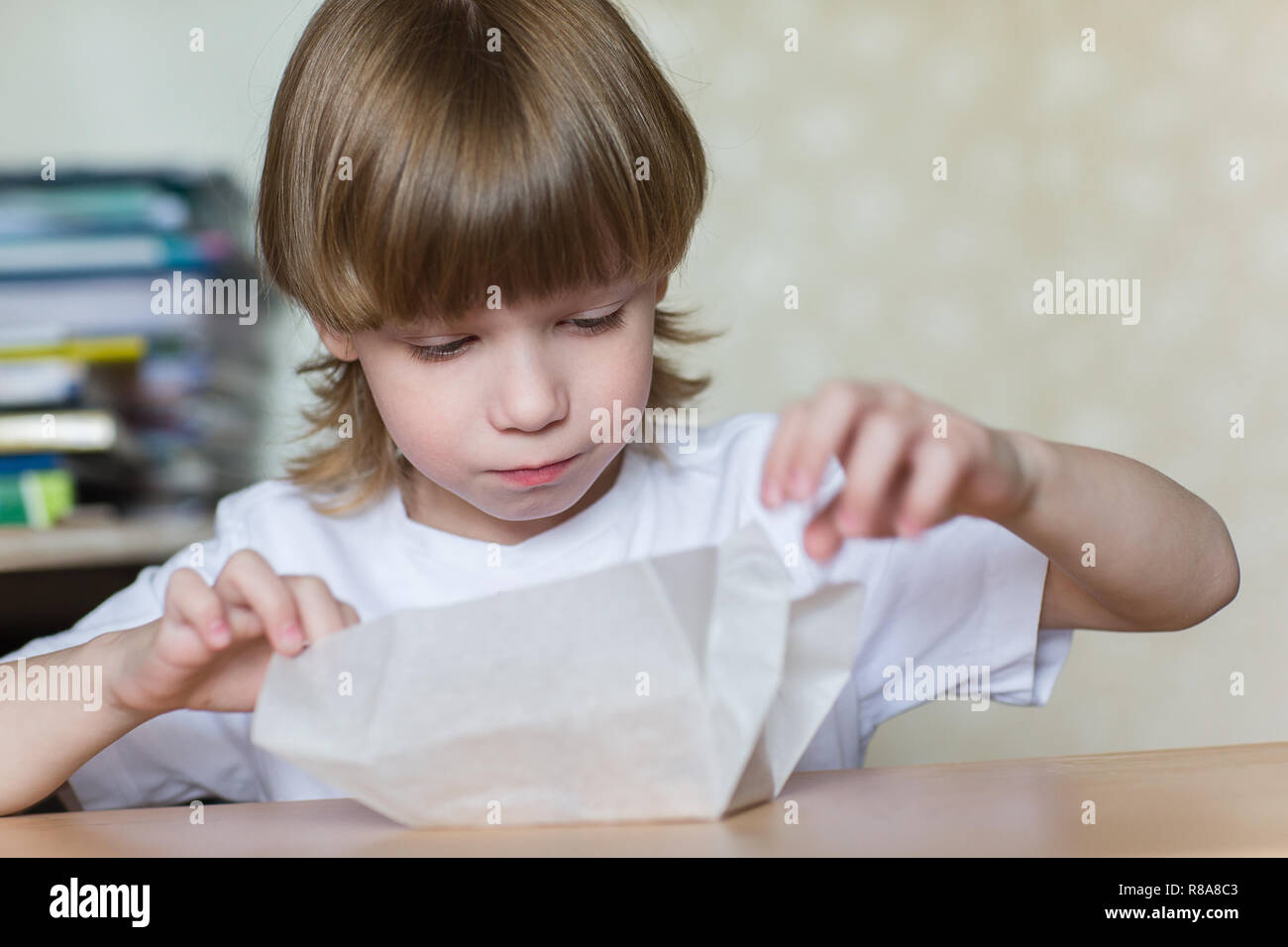 Kind öffnet ein Geschenk in weißes Papier eingewickelt. Stockfoto
