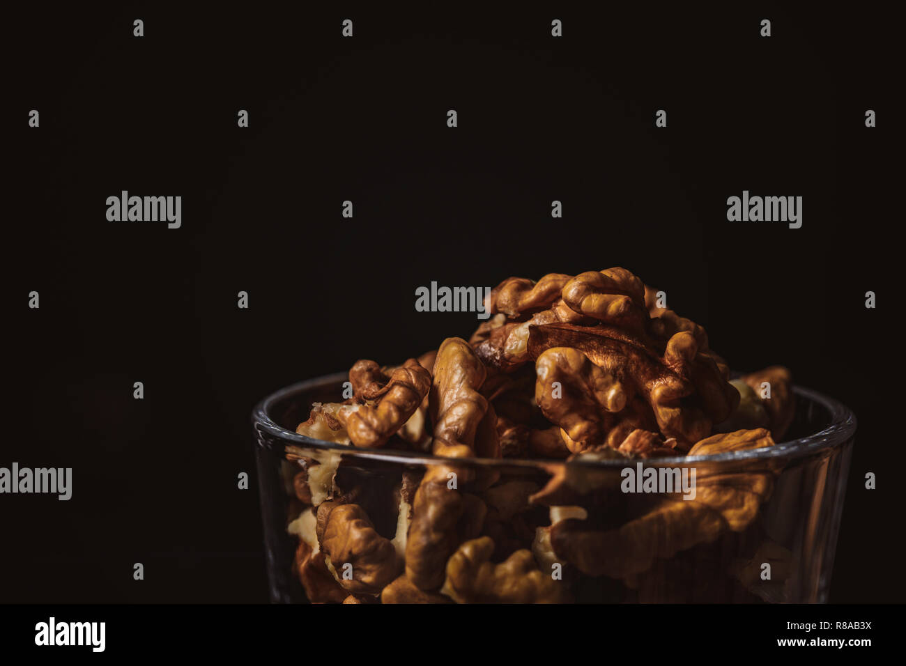 Nahaufnahme Blick auf ohne Schale Walnüsse in Glas auf schwarzem Hintergrund Stockfoto