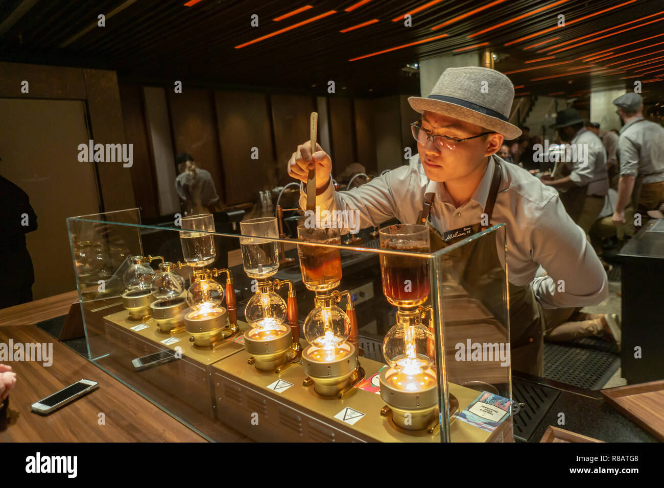 New York, USA. 14. Dezember, 2018. Ein Barista bereitet Siphon Kaffee im Starbucks finden Rösterei in Chelsea in New York auf der großen Eröffnung Tag, Freitag, 14. Dezember 2018. Die 23.000-Quadratfuß-Kaffee der Himmel ist das vierte von gehobenen Positionen des Unternehmens, mit mehreren Coffee Bars, eine Niederlassung der italienischen Bäckerei Erfüllungsrisiken (Wer liefert Backwaren zu Starbucks) und eine offene und Besucher können den Röstprozess zu beobachten. (© Richard B. Levine) Credit: Richard Levine/Alamy leben Nachrichten Stockfoto New York, USA. 14. Dezember, 2018. Ein Barista bereitet Siphon Kaffee im Starbucks finden Rösterei in Chelsea in New York auf der großen Eröffnung Tag, Freitag, 14. Dezember 2018. Die 23.000-Quadratfuß-Kaffee der Himmel ist das vierte von gehobenen Positionen des Unternehmens, mit mehreren Coffee Bars, eine Niederlassung der italienischen Bäckerei Erfüllungsrisiken (Wer liefert Backwaren zu Starbucks) und eine offene und Besucher können den Röstprozess zu beobachten. (© Richard B. Levine) Credit: Richard Levine/Alamy leben Nachrichten Stockfoto