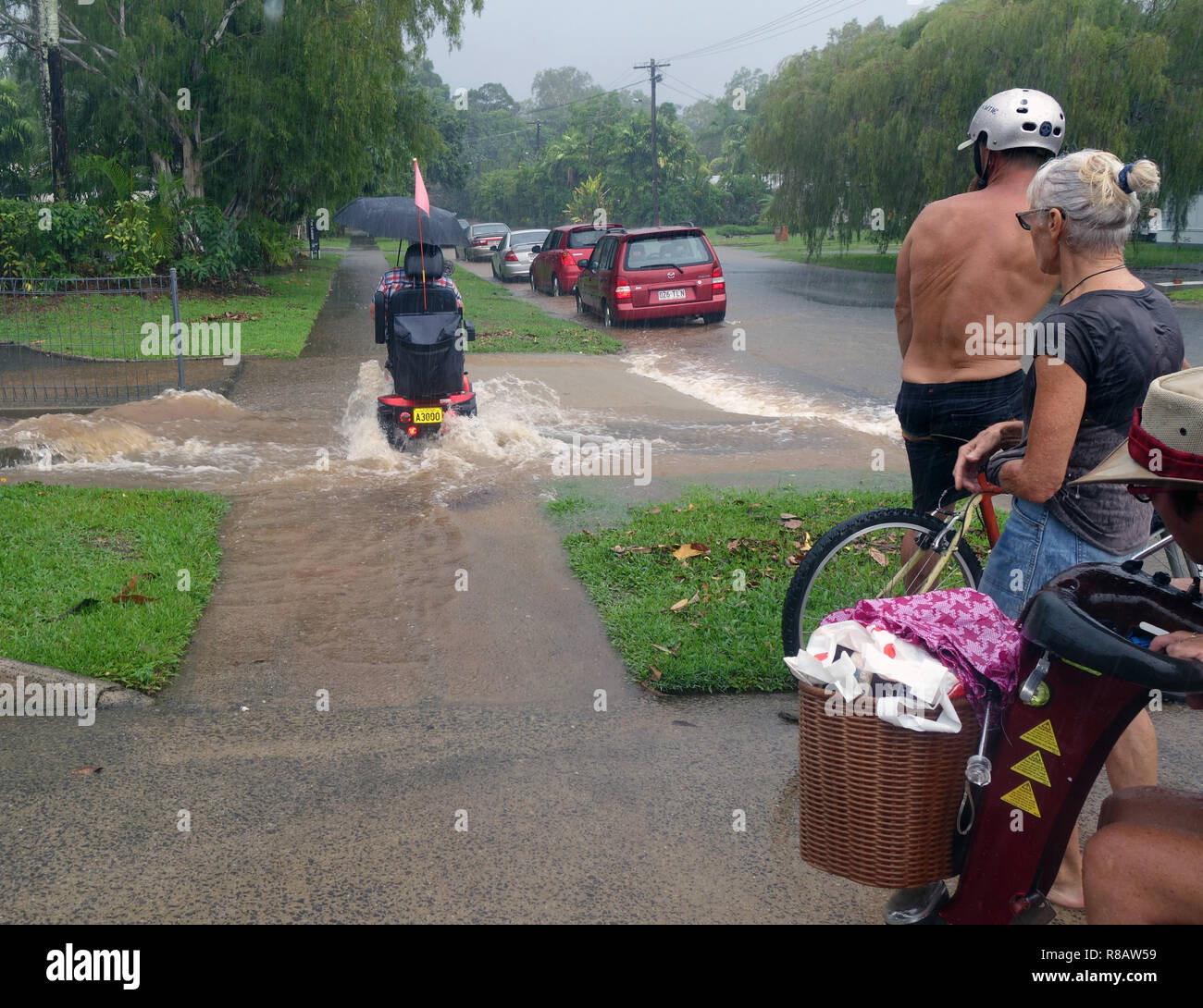 Cairns, Australien, 15. Dez 2018. Erste Stürme aus tropischen Zyklon Owen haben lokalisierte Überschwemmung in Far North Queensland verursacht. Die Einheimischen beobachten, wie Menschen auf Mobilität scooter fährt durch Hochwasser im Vorort Edge Hill, Cairns, Queensland, Australien. Credit: Suzanne Long/Alamy leben Nachrichten Stockfoto