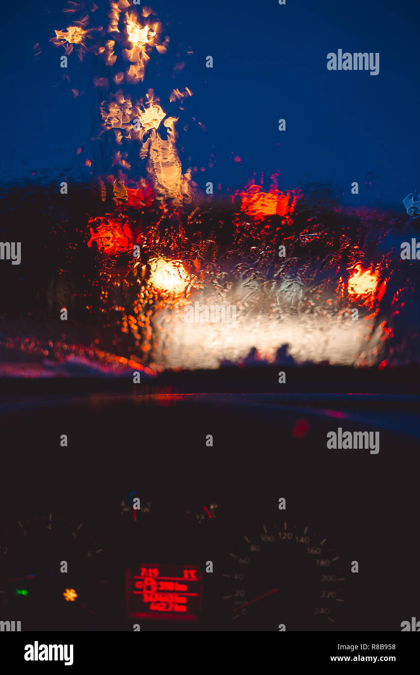 Nacht Stadt Straße durch die Windschutzscheibe Autos abstrakt hintergrund Wasser Tropfen auf dem Glas Licht und Regen. Stockfoto