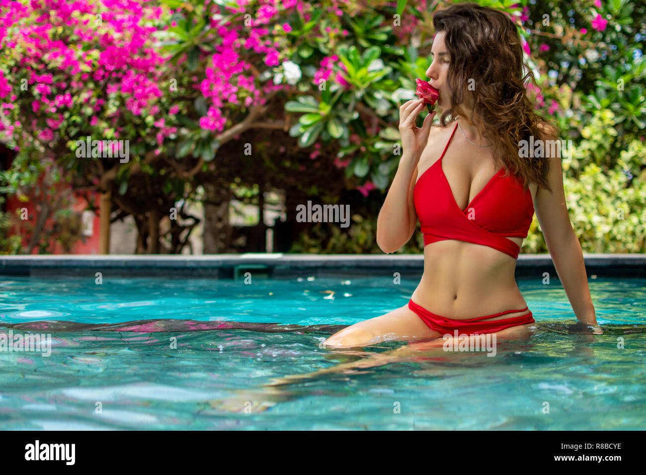 Mädchen entspannend und das Essen von Früchten Platte durch den Pool. Exotische Mango, Ananas, Drachenfrucht Sommer Diät am Pool. Tropical Beach Lifestyle Stockfoto