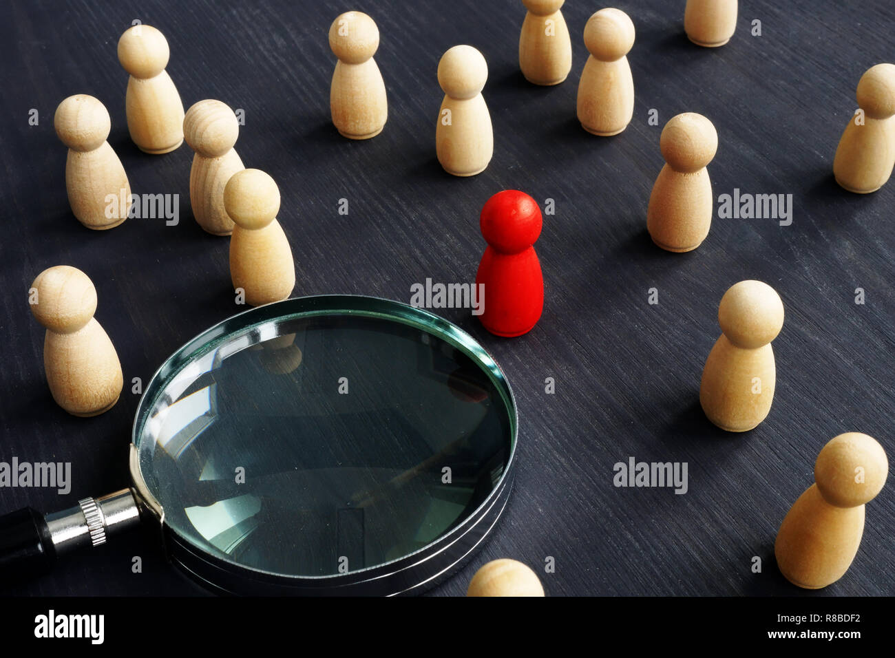 Holzfiguren und Lupe. Personalauswahl Konzept. Die Einstellung der Mitarbeiter zu arbeiten. Stockfoto