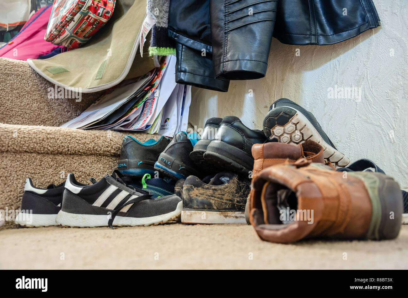 Familie Schuhe in einem chaotischen Haufen auf dem Boden an der Unterseite der Treppe in einem Heim verlassen. Stockfoto