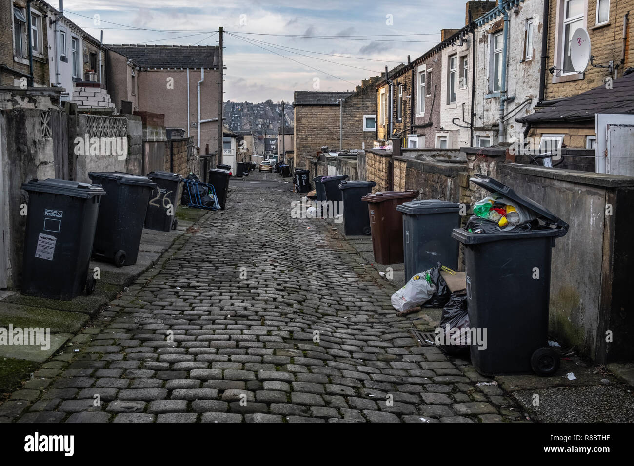 Wheelie Bins und Müll in einer Gasse in der ehemaligen Mühle Stadt Nelson, Lancashire Stockfoto