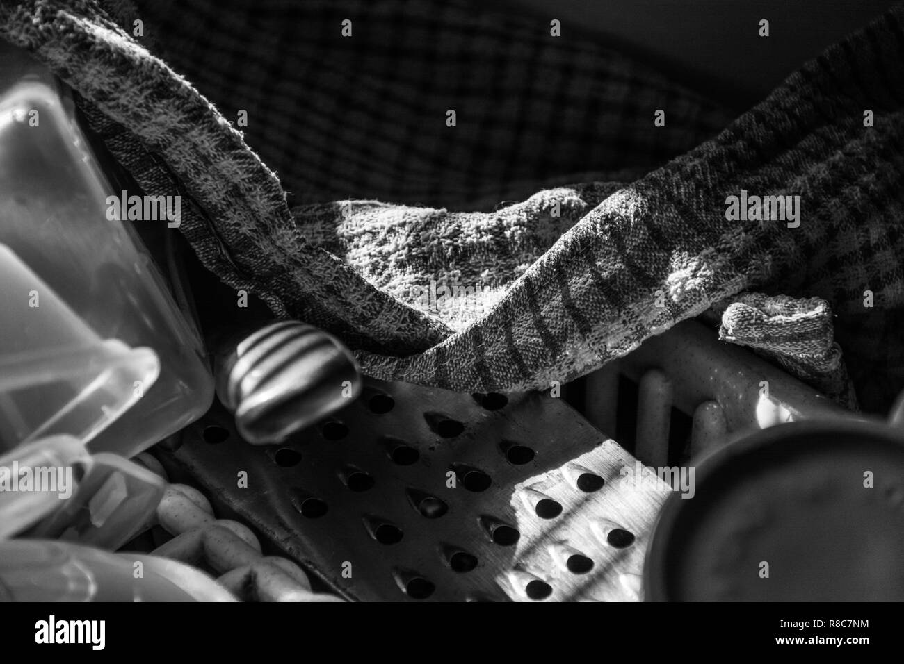 Schwarz und weiß Detail der verschiedenen Elemente auf einem abtropffläche, Großbritannien. Geschirrtuch, Käsereibe, Messer Griff. Stockfoto