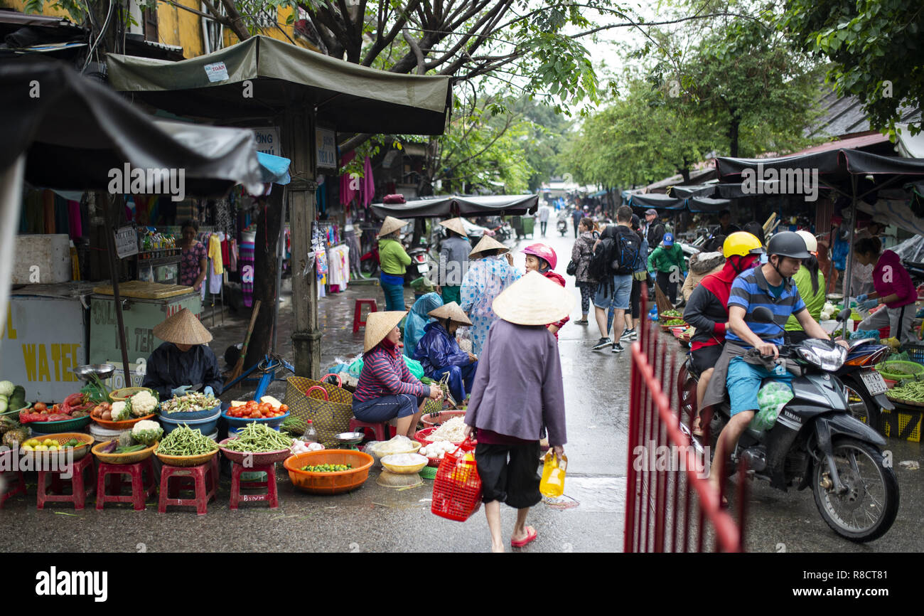 Einige Leute mit den typischen vietnamesischen konische Hut sind frisches Gemüse in einer Street Market, Hoi An. Stockfoto