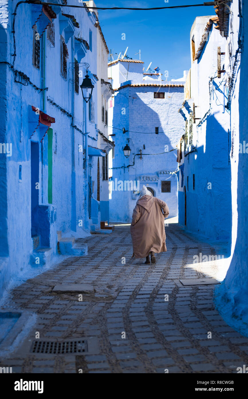 Ein Mann mit einem traditionellen Kleid ist zu Fuß in der schönen blauen Medina von Tanger, Marokko. Stockfoto