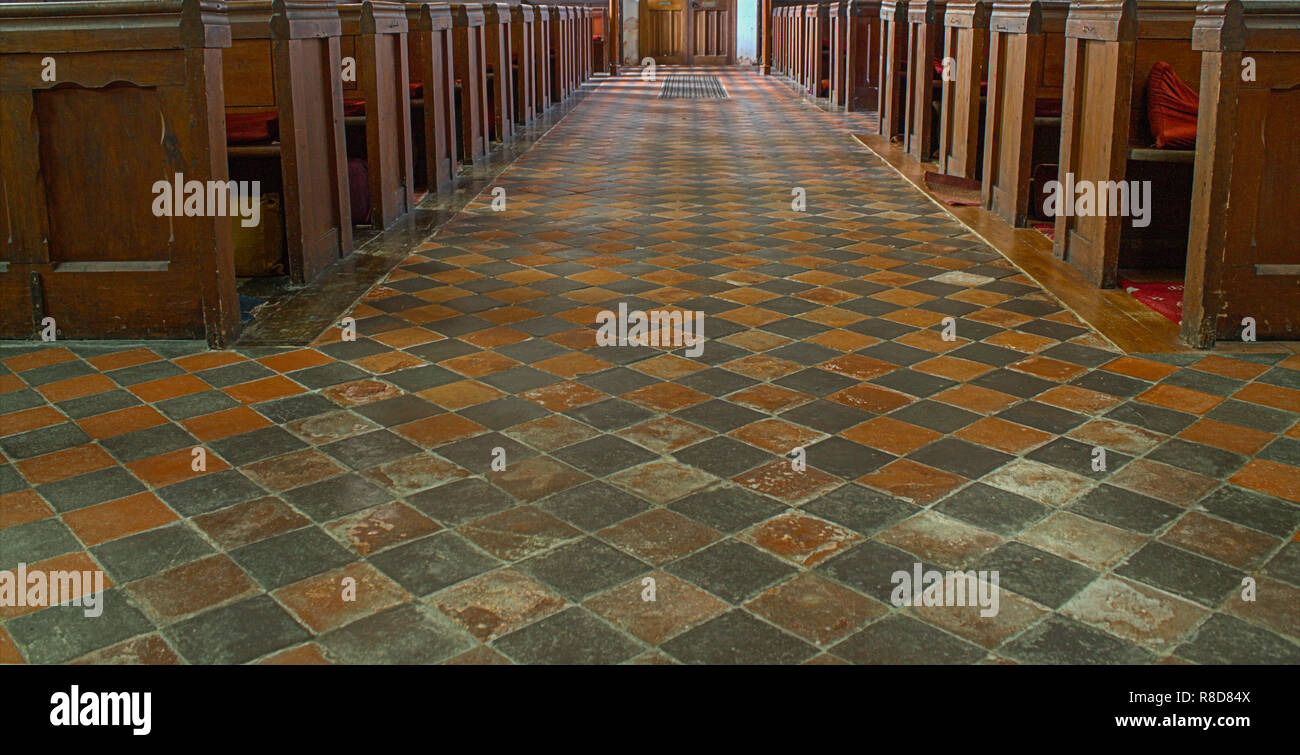 Leere Kirchenbänke mit Rautenmuster Fliesenboden Stockfoto