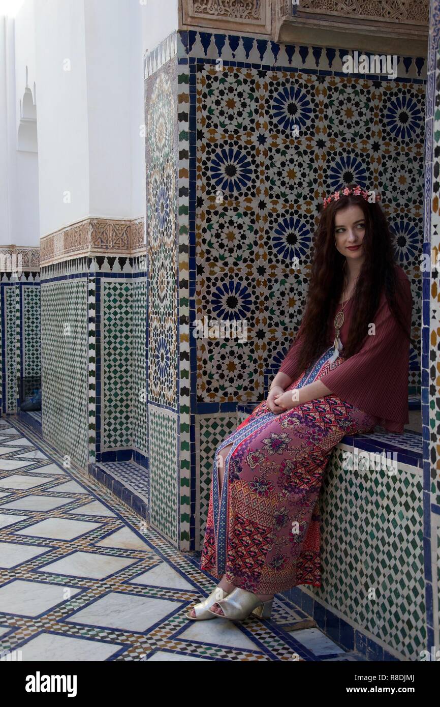 Ein Hippie weiblichen causasian Touristische mit Blumen im Haar sitzt in einem marokkanischen Innenhof umgeben von eleganten Fliesen Stockfoto