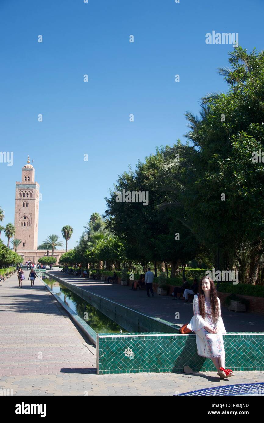 Eine weibliche westlichen Touristen ganz in Weiß gekleidet posiert vor der Moschee Koutoubia, Marrakesch, Marokko Stockfoto