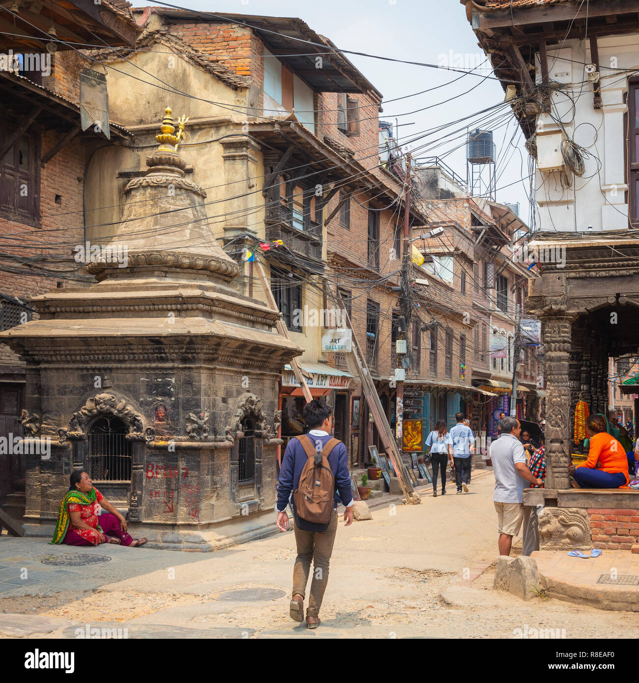 Junger Mann zu Fuß vorbei an kleinen Tempel und Stadt Straße in Patan, Kathmandu, Nepal. Stockfoto