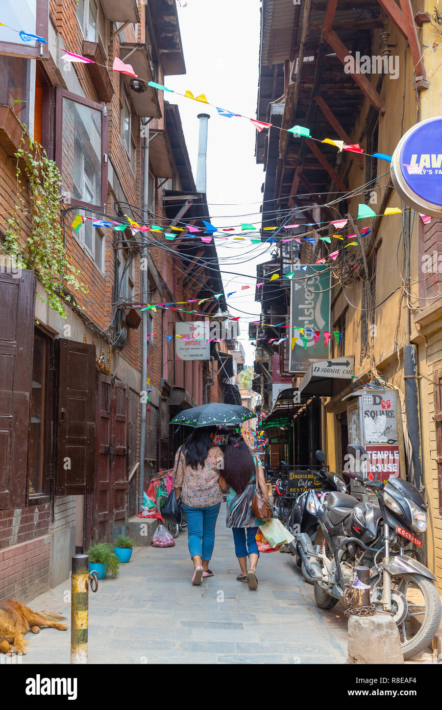 Mutter und Tochter halten sich einen Sonnenschirm und zu Fuß die Straße runter in Patan, Kathmandu, Nepal. Stockfoto