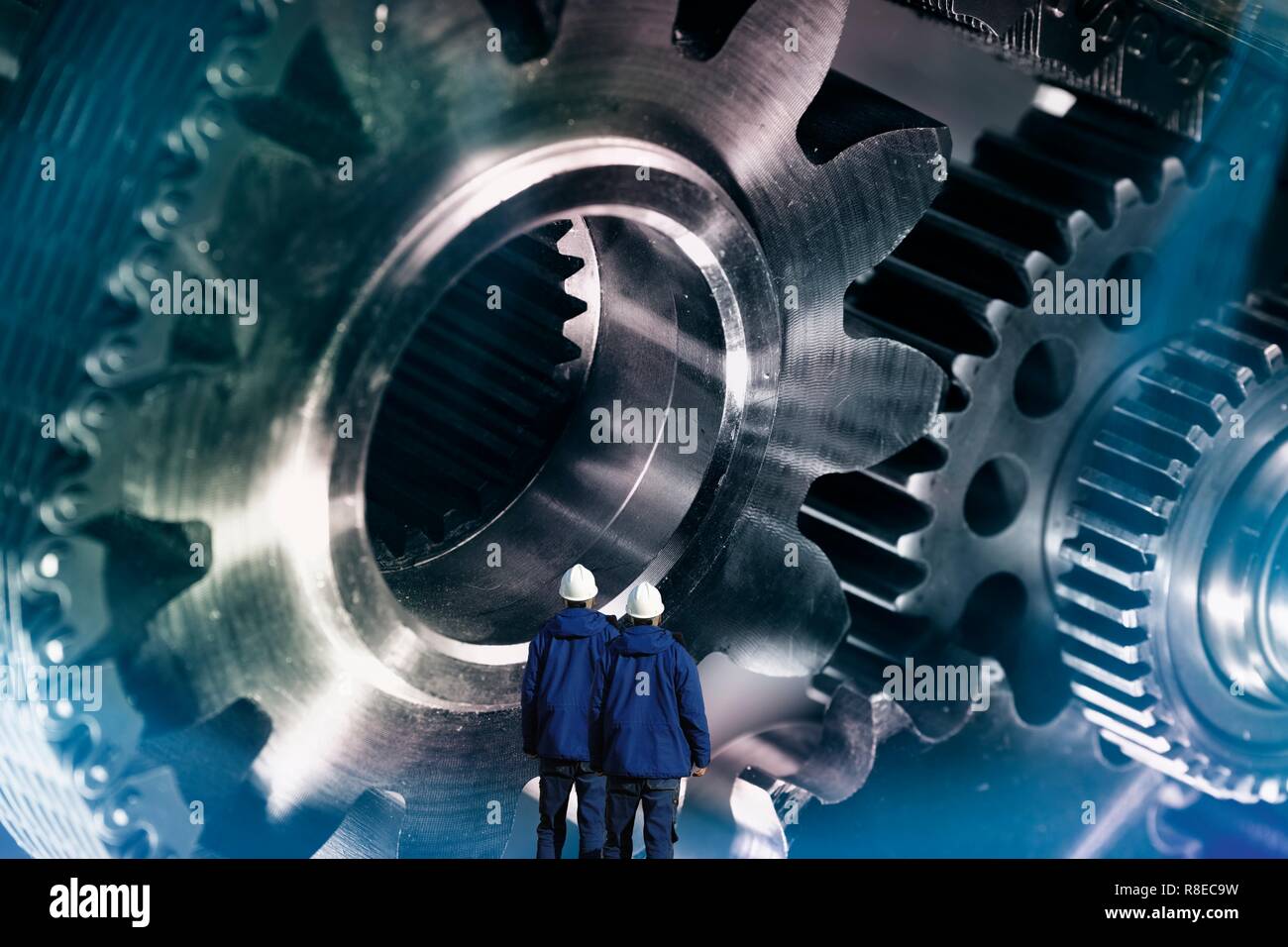 Engineering, konzeptuelle Bild. Zwei Industrie Arbeitnehmer mit großen Zahnräder und Cog Maschinen durch Ketten angetrieben. Stockfoto