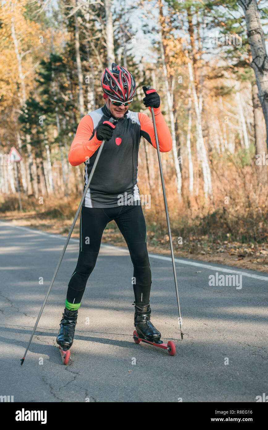 Training ein Athlet auf der Walze Skater. Biathlon Fahrt auf dem Roller Ski  mit Skistöcke, im Helm. Herbst Training. Roller Sport. Erwachsene Mann rid  Stockfotografie - Alamy