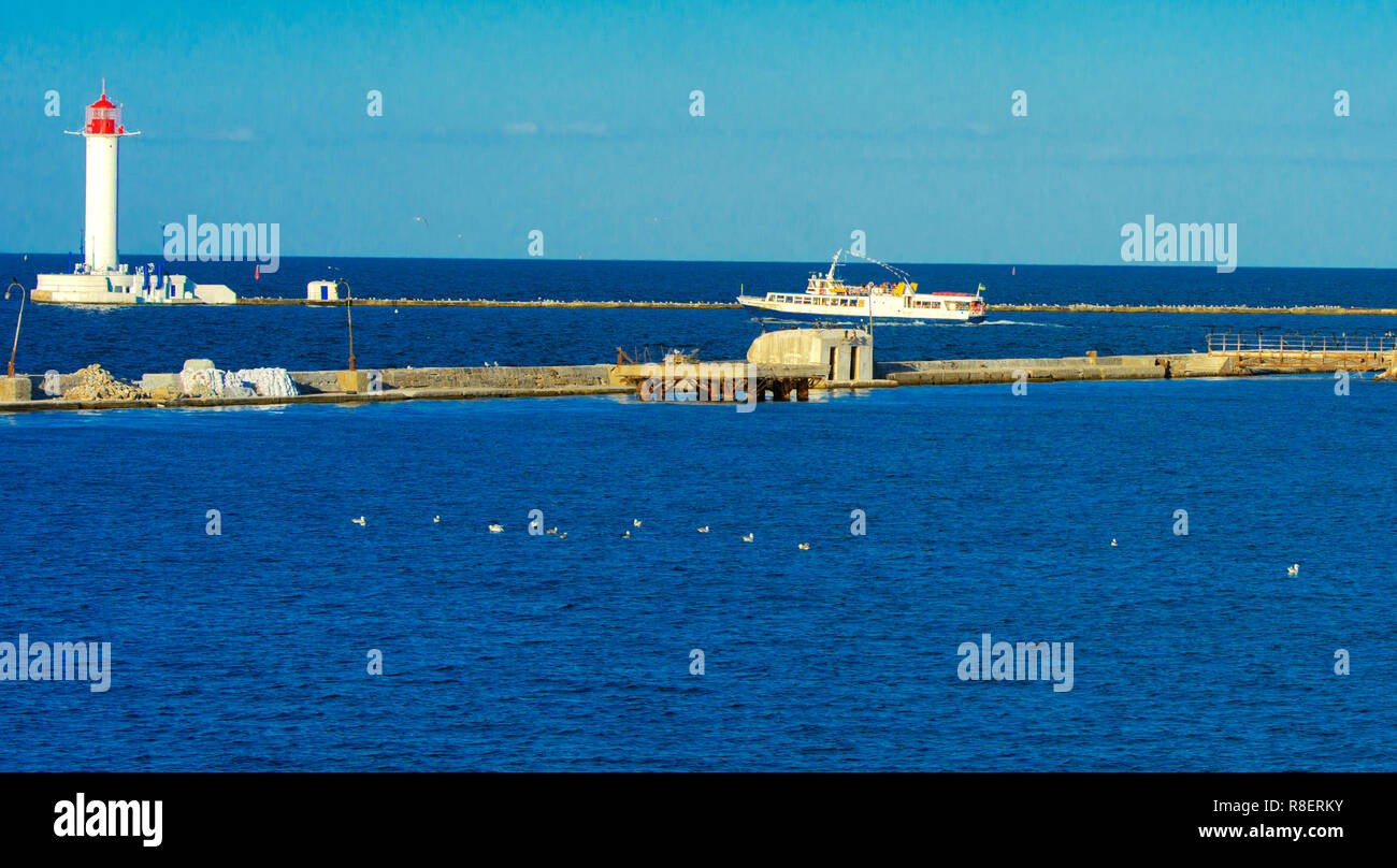 Ein Leuchtturm im Meer am Eingang zum Hafen vor dem Hintergrund eines schönen Abends blauer Himmel in weichen Farben. Sommer Seascape. Weiße Leucht Stockfoto