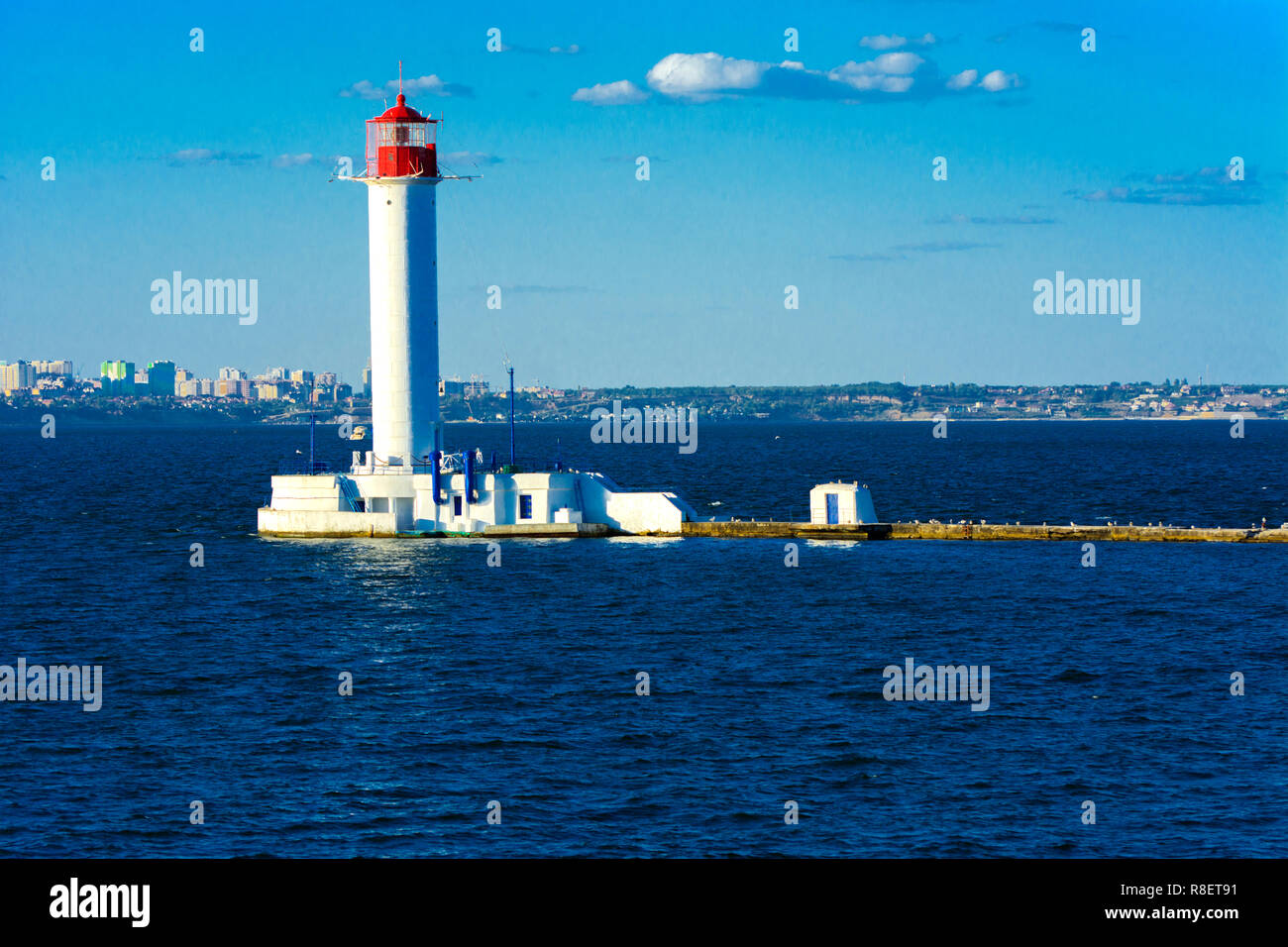 Ein Leuchtturm im Meer am Eingang zum Hafen vor dem Hintergrund eines schönen Abends blauer Himmel in weichen Farben. Sommer Seascape. Weiße Leucht Stockfoto