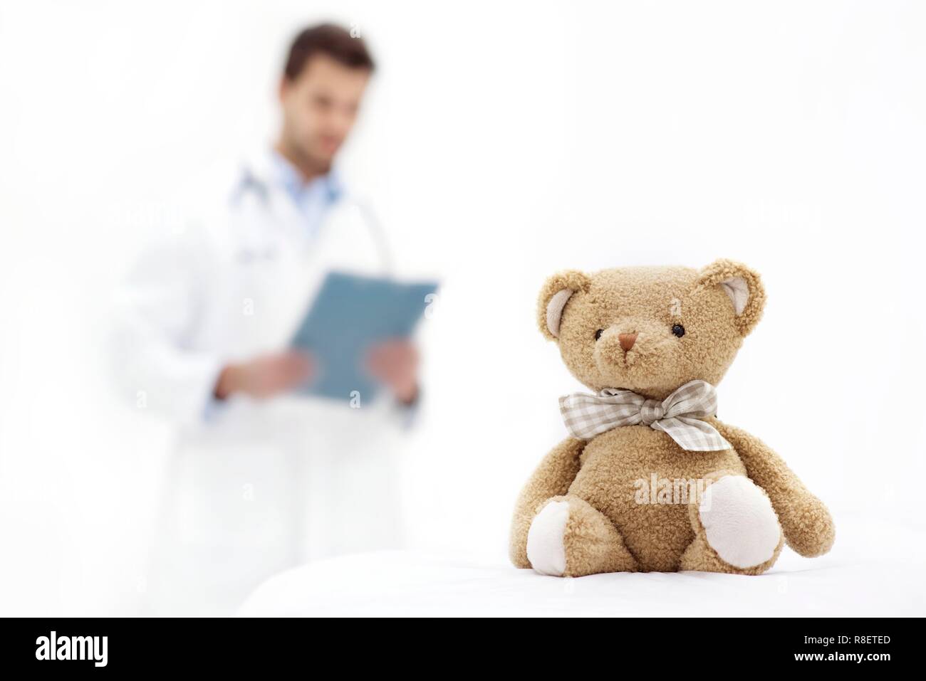 Teddybär mit männlicher Arzt im Hintergrund halten Zwischenablage. Stockfoto