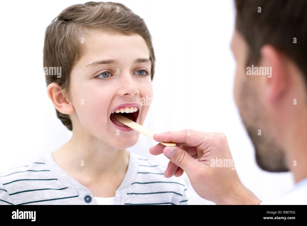 Arzt mit zungenspatel, Boy's Mund. Stockfoto