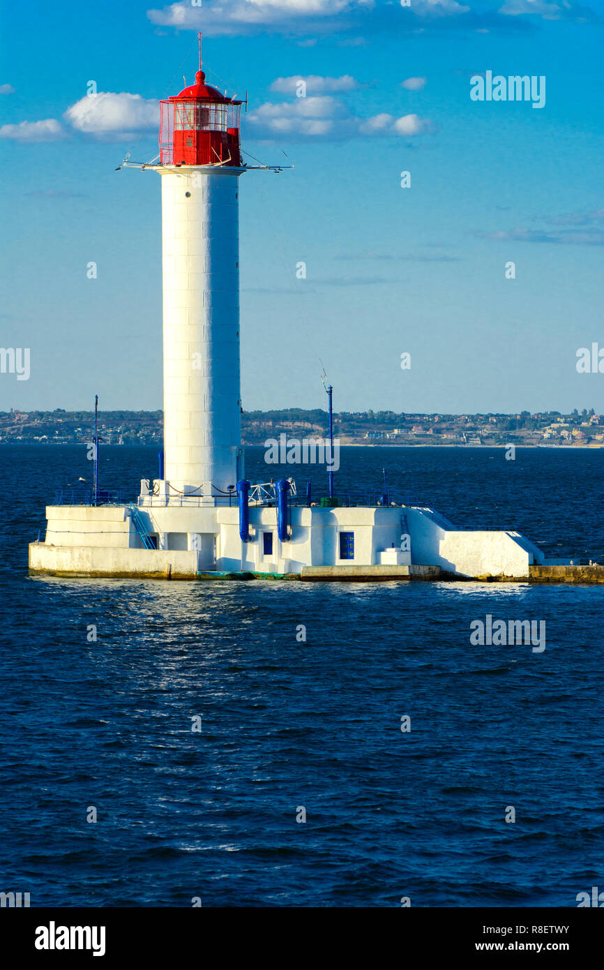 Ein Leuchtturm im Meer am Eingang zum Hafen vor dem Hintergrund eines schönen Abends blauer Himmel in weichen Farben. Sommer Seascape. Weiße Leucht Stockfoto