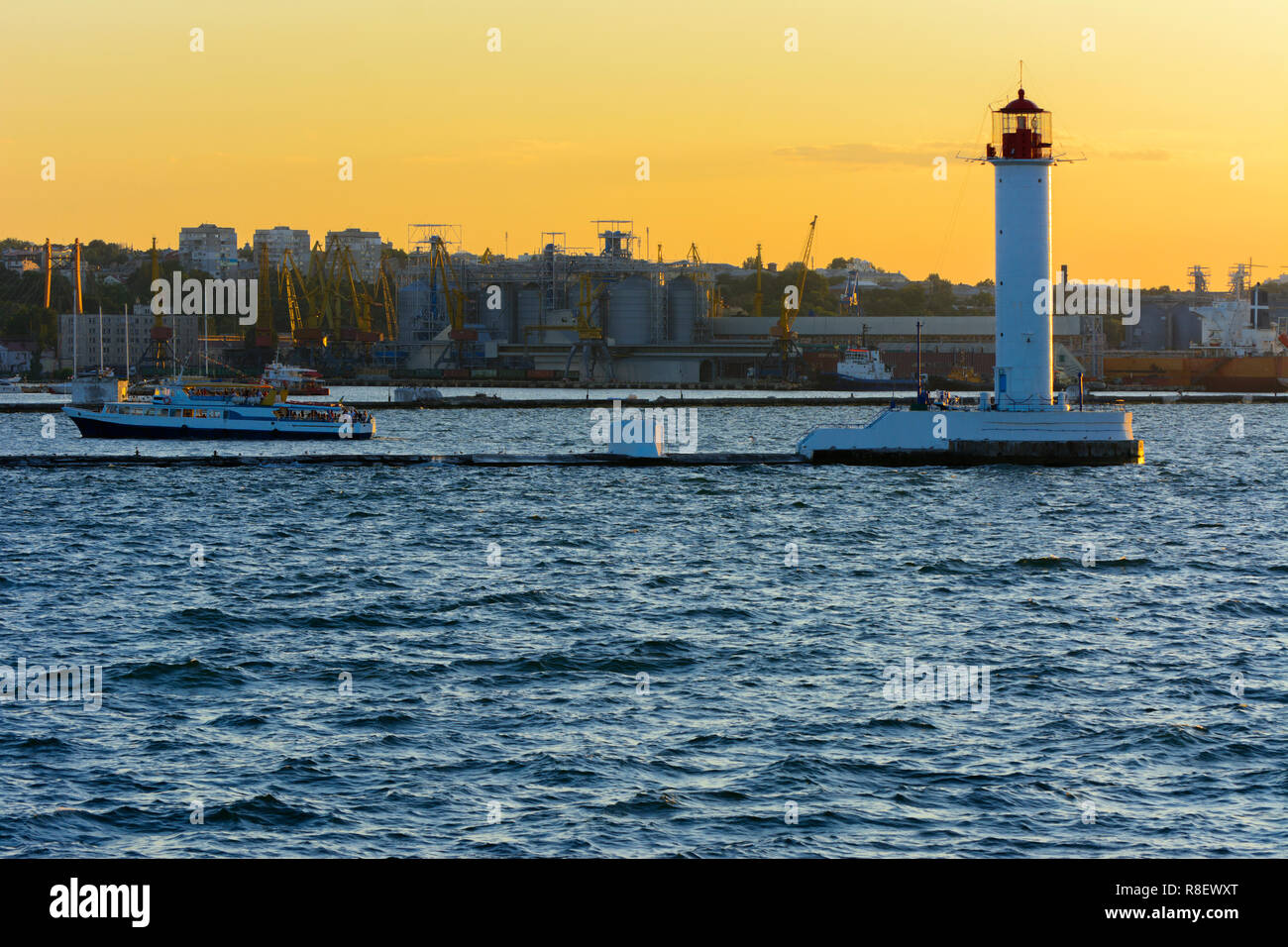 Ein Leuchtturm im Meer am Eingang zum Hafen vor dem Hintergrund eines schönen Abends blauer Himmel in weichen Farben. Sommer Seascape. Weiße Leucht Stockfoto