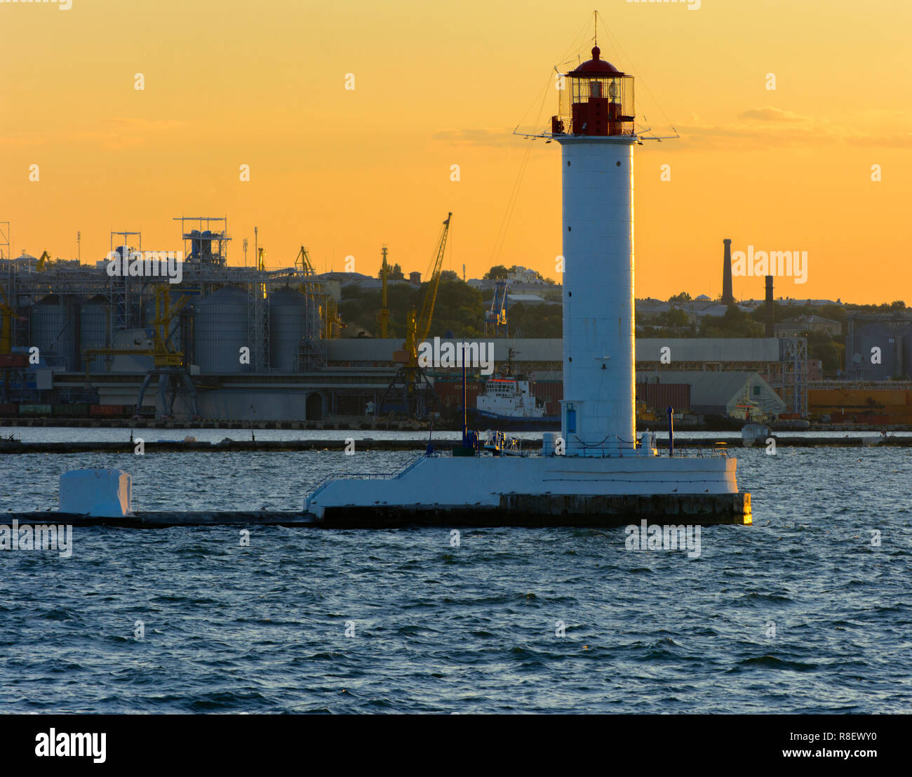 Ein Leuchtturm im Meer am Eingang zum Hafen vor dem Hintergrund eines schönen Abends blauer Himmel in weichen Farben. Sommer Seascape. Weiße Leucht Stockfoto