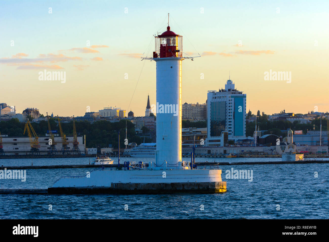 Ein Leuchtturm im Meer am Eingang zum Hafen vor dem Hintergrund eines schönen Abends blauer Himmel in weichen Farben. Sommer Seascape. Weiße Leucht Stockfoto