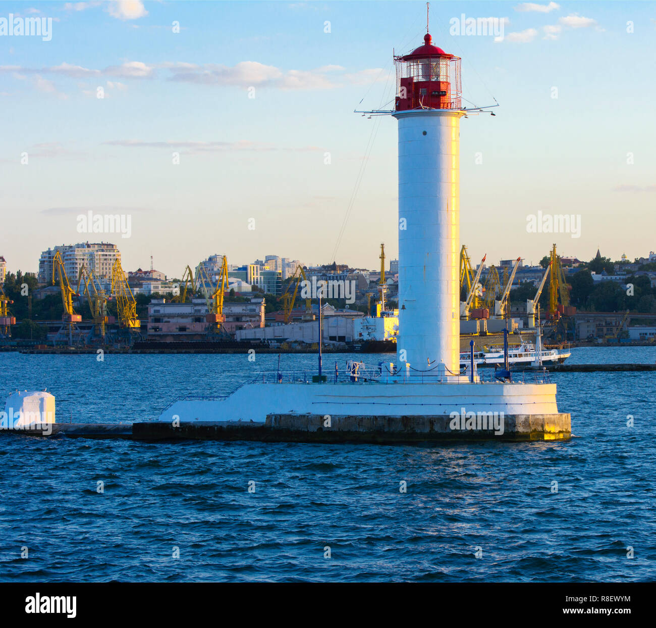 Ein Leuchtturm im Meer am Eingang zum Hafen vor dem Hintergrund eines schönen Abends blauer Himmel in weichen Farben. Sommer Seascape. Weiße Leucht Stockfoto