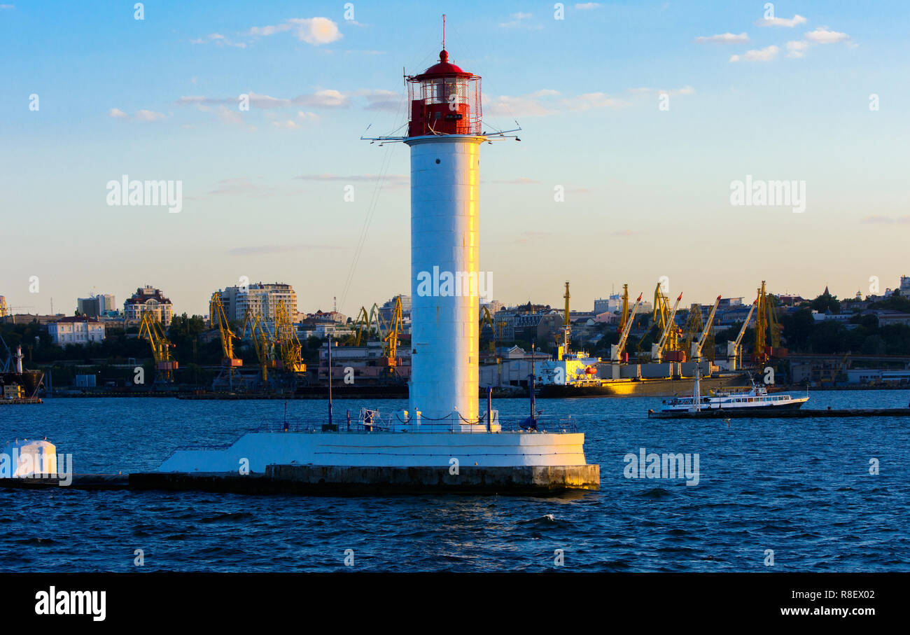 Ein Leuchtturm im Meer am Eingang zum Hafen vor dem Hintergrund eines schönen Abends blauer Himmel in weichen Farben. Sommer Seascape. Weiße Leucht Stockfoto