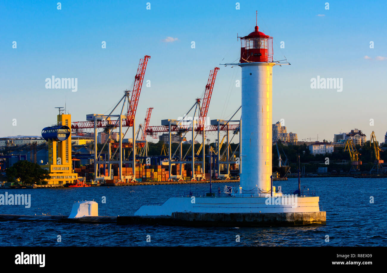 Ein Leuchtturm im Meer am Eingang zum Hafen vor dem Hintergrund eines schönen Abends blauer Himmel in weichen Farben. Sommer Seascape. Weiße Leucht Stockfoto