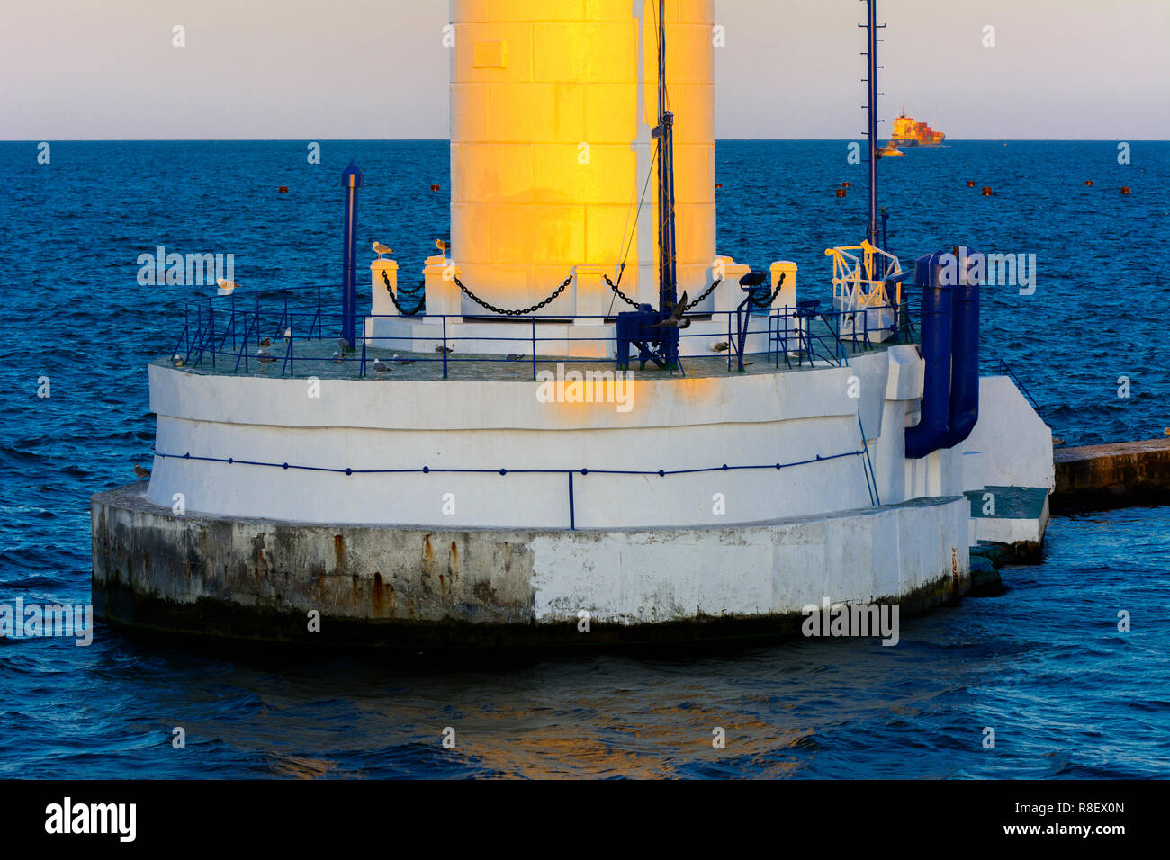 Der untere Teil der Leuchtturm an der Einfahrt zum Hafen auf dem Hintergrund eines schönen Abends blauer Himmel in weichen Farben. Sommer Seascape. Weiße Leucht Stockfoto