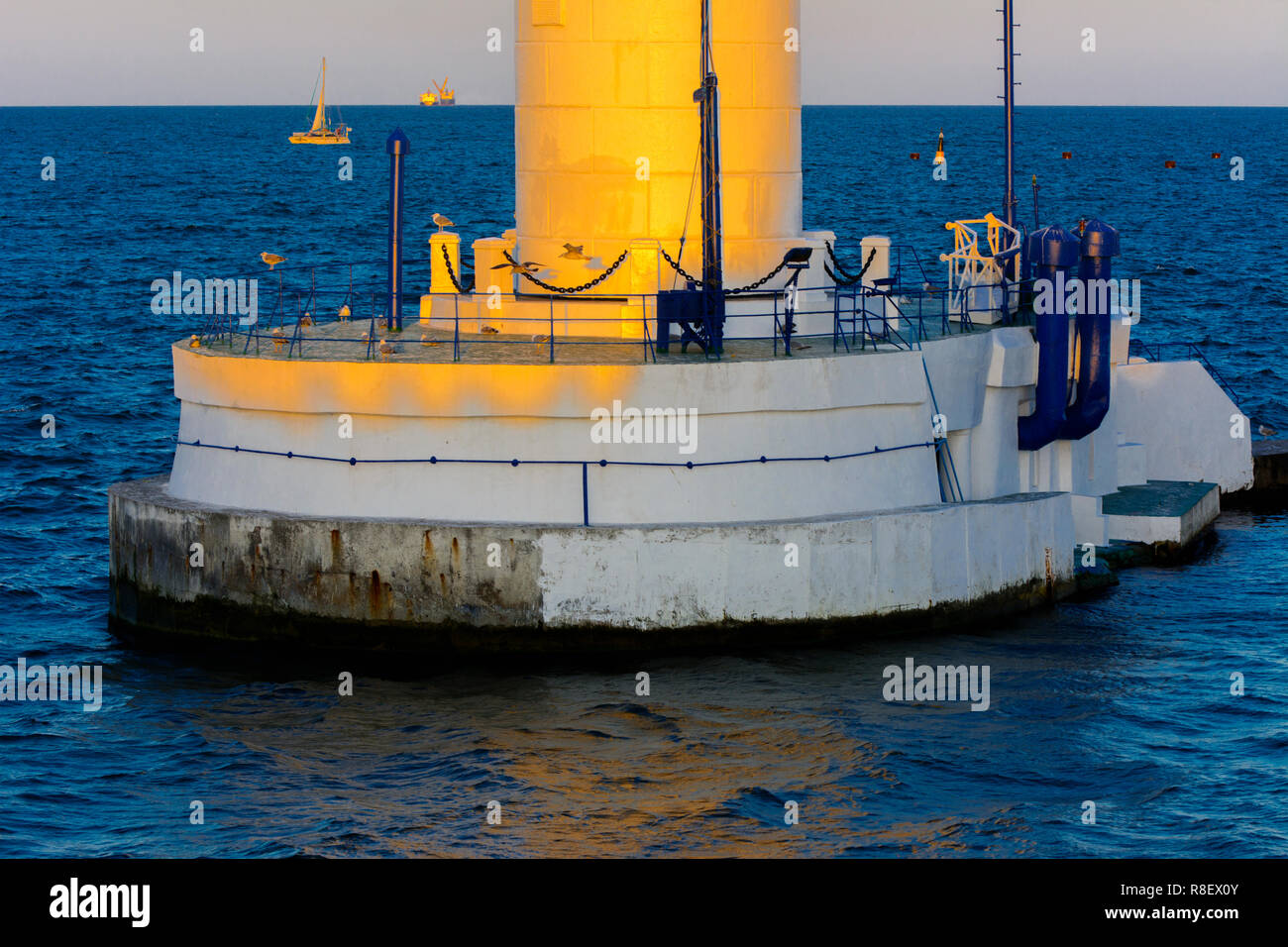 Der untere Teil der Leuchtturm an der Einfahrt zum Hafen auf dem Hintergrund eines schönen Abends blauer Himmel in weichen Farben. Sommer Seascape. Weiße Leucht Stockfoto