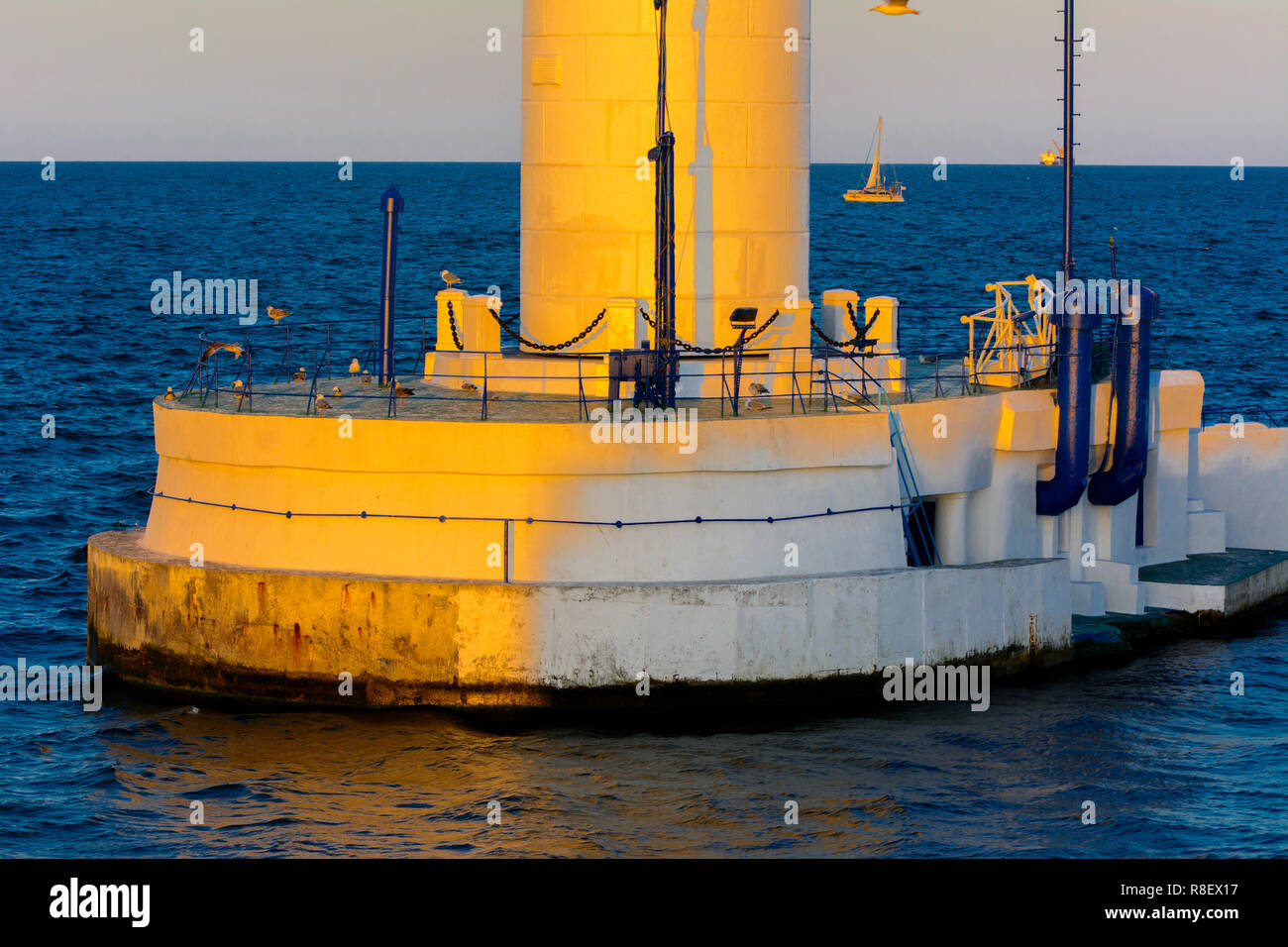 Der untere Teil der Leuchtturm an der Einfahrt zum Hafen auf dem Hintergrund eines schönen Abends blauer Himmel in weichen Farben. Sommer Seascape. Weiße Leucht Stockfoto