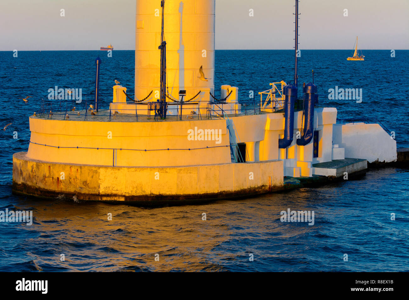 Der untere Teil der Leuchtturm an der Einfahrt zum Hafen auf dem Hintergrund eines schönen Abends blauer Himmel in weichen Farben. Sommer Seascape. Weiße Leucht Stockfoto