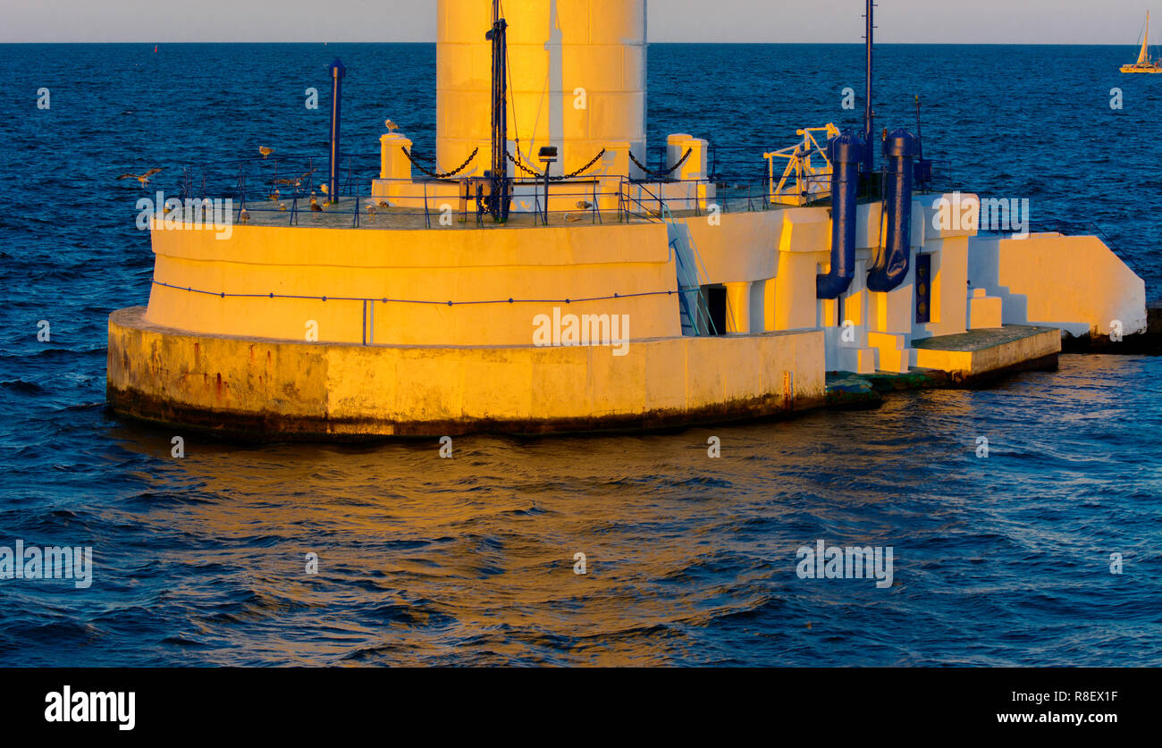 Der untere Teil der Leuchtturm an der Einfahrt zum Hafen auf dem Hintergrund eines schönen Abends blauer Himmel in weichen Farben. Sommer Seascape. Weiße Leucht Stockfoto