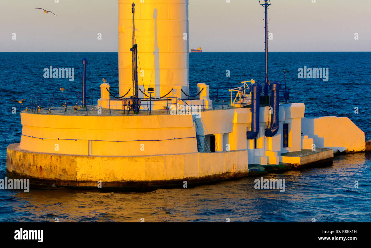 Der untere Teil der Leuchtturm an der Einfahrt zum Hafen auf dem Hintergrund eines schönen Abends blauer Himmel in weichen Farben. Sommer Seascape. Weiße Leucht Stockfoto