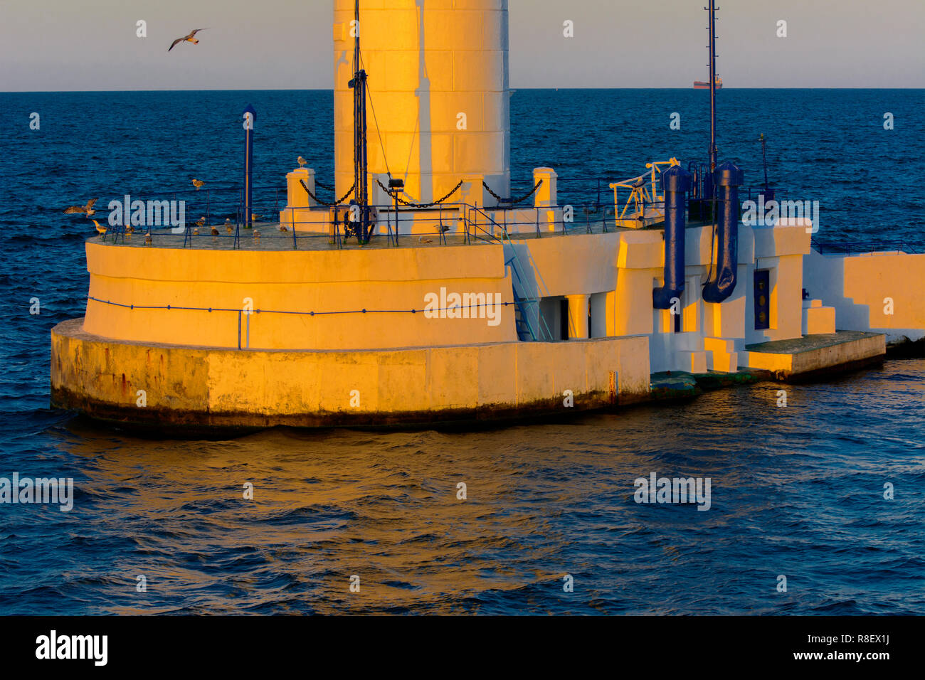 Der untere Teil der Leuchtturm an der Einfahrt zum Hafen auf dem Hintergrund eines schönen Abends blauer Himmel in weichen Farben. Sommer Seascape. Weiße Leucht Stockfoto