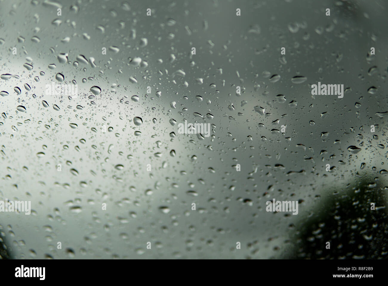 Regentropfen auf dem Auto Glas Hintergrund. Straße Blick durch Fenster mit Regentropfen, das Fahren bei Regen. Abstrakte Verkehr in regen Tag. Blick aus dem Auto Meer Stockfoto